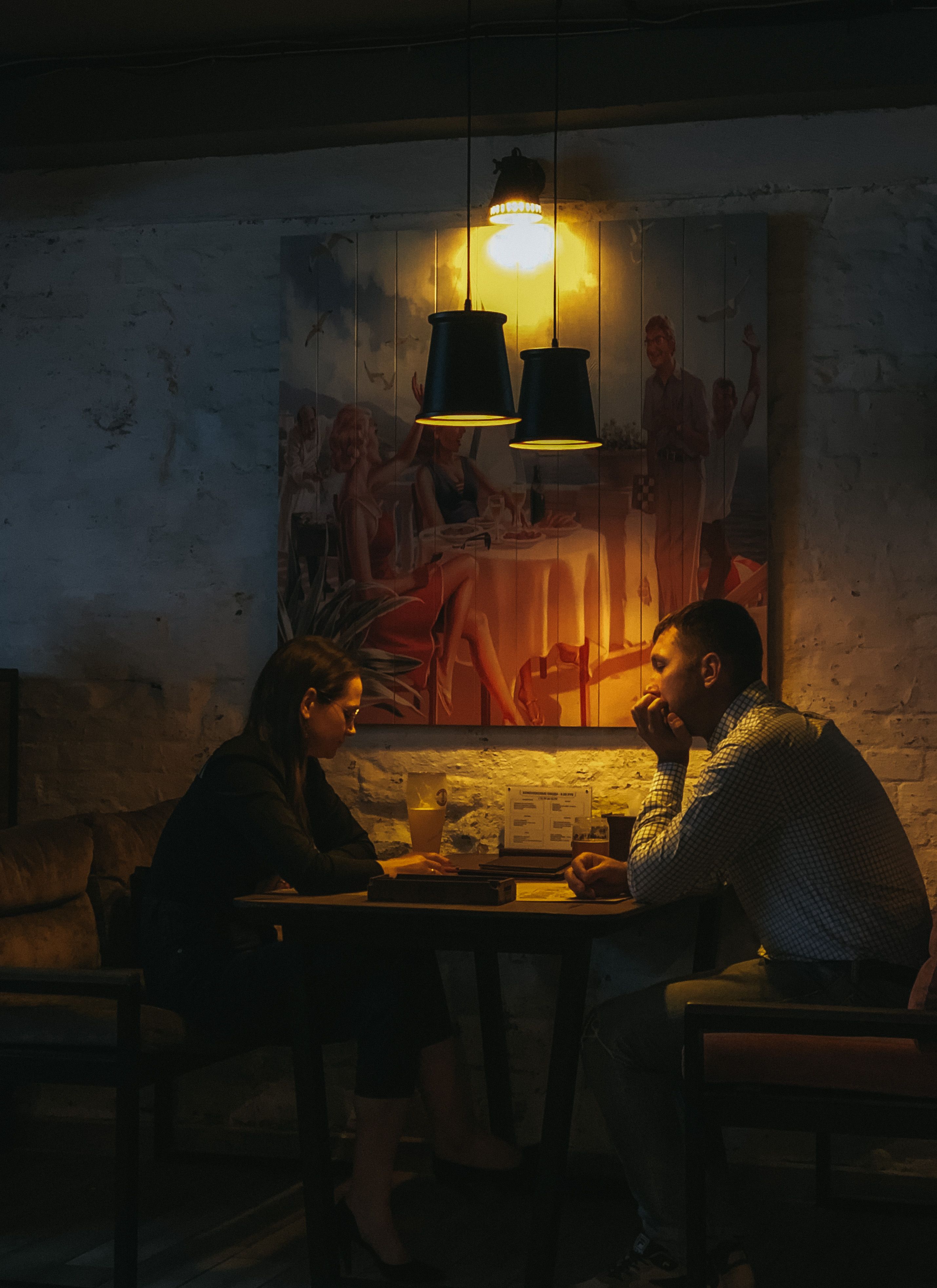Couple enjoying a relaxed dinner conversation under warm restaurant lighting