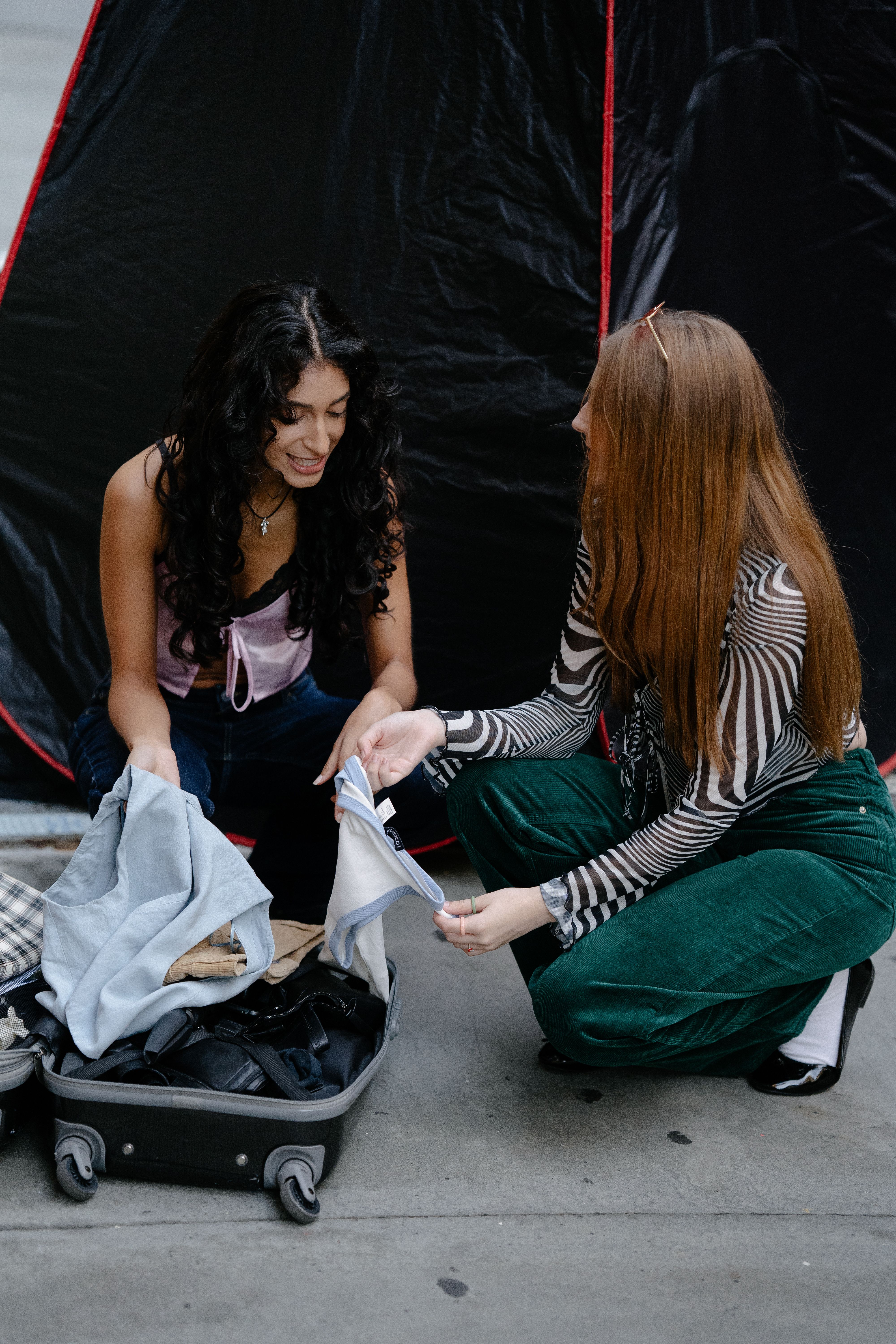 Two women packing a suitcase together and smiling before a trip