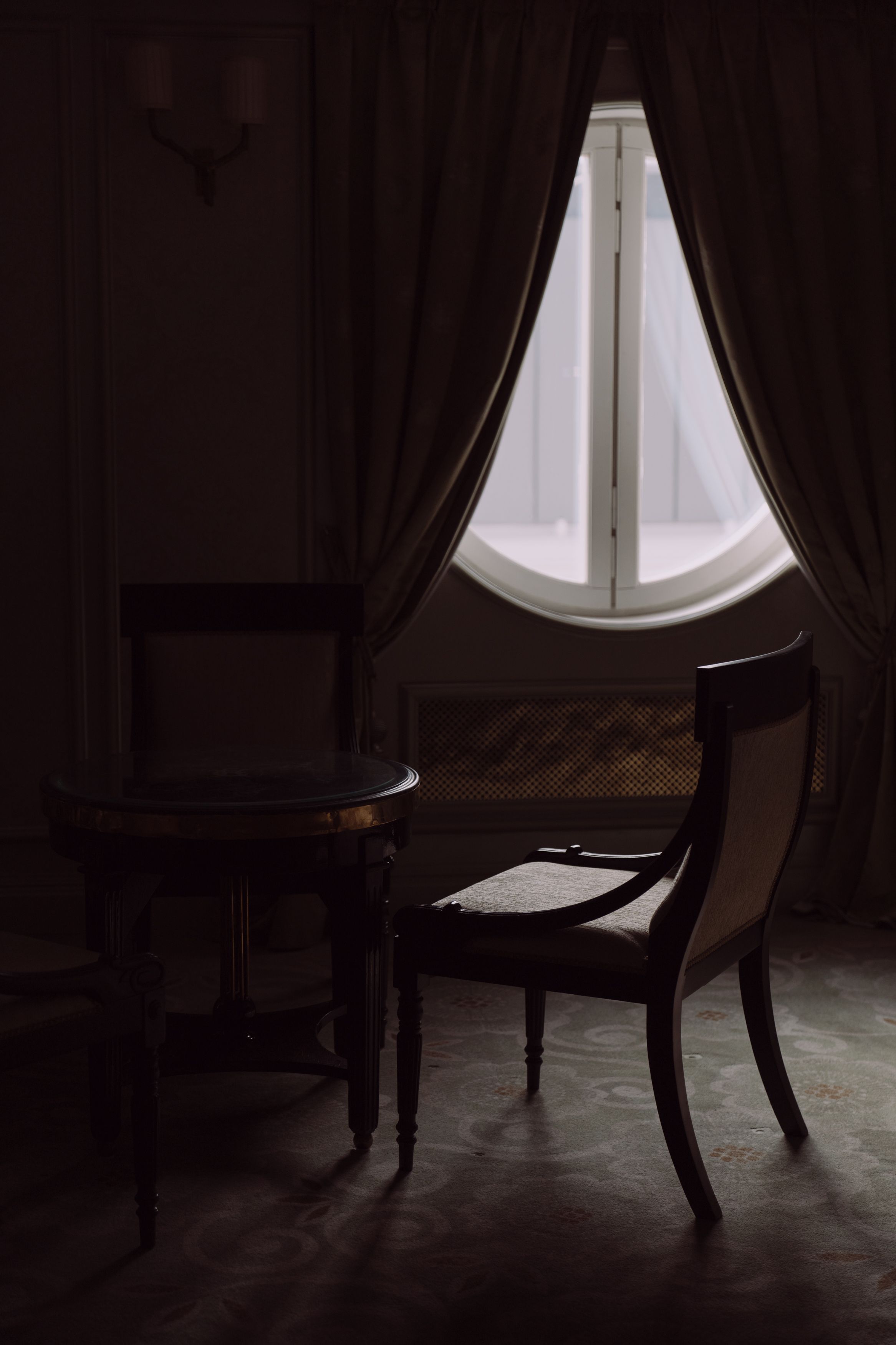 Sophisticated hotel room interior with a large arched window, representing shared travel accommodations